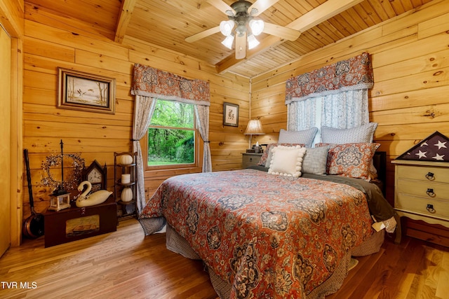 bedroom with ceiling fan, beam ceiling, wood finished floors, wooden ceiling, and wooden walls