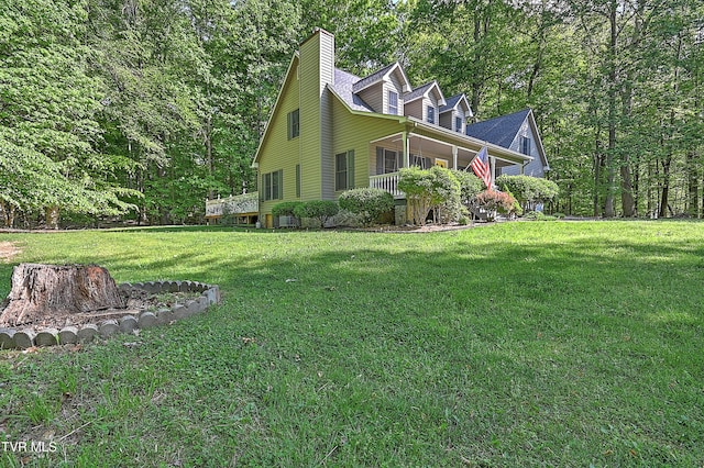 view of side of home featuring a lawn, a view of trees, and a chimney