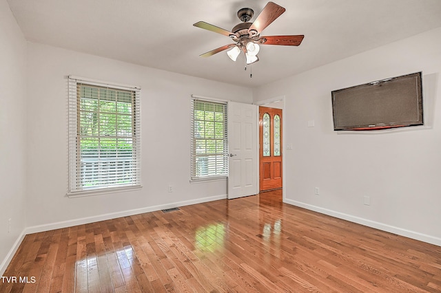 empty room featuring baseboards, visible vents, ceiling fan, and light wood-type flooring