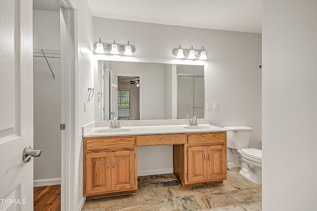 bathroom featuring double vanity, a sink, a shower with door, and toilet