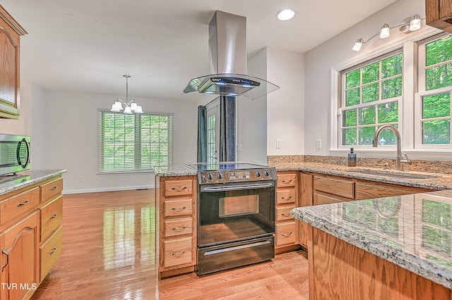 kitchen with a sink, black electric range, light wood-style flooring, stainless steel microwave, and island exhaust hood