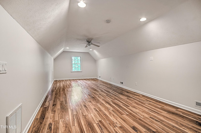additional living space featuring ceiling fan, visible vents, wood finished floors, baseboards, and lofted ceiling