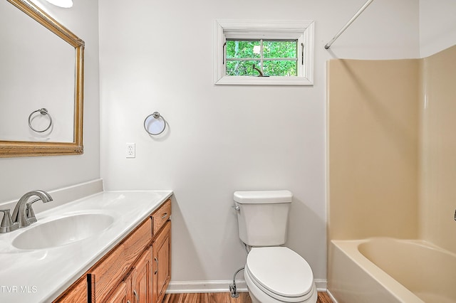 bathroom featuring vanity, baseboards, wood finished floors, and toilet