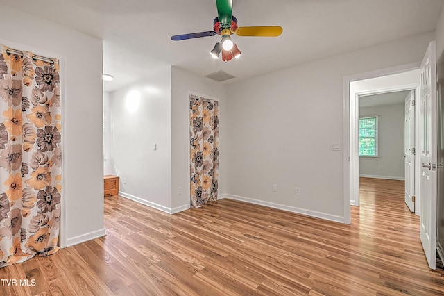 empty room with light wood-style floors, baseboards, a ceiling fan, and visible vents