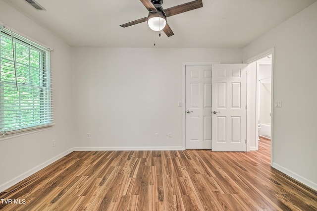 unfurnished bedroom with baseboards, a ceiling fan, wood finished floors, and visible vents