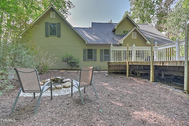 rear view of house with roof with shingles and an outdoor fire pit