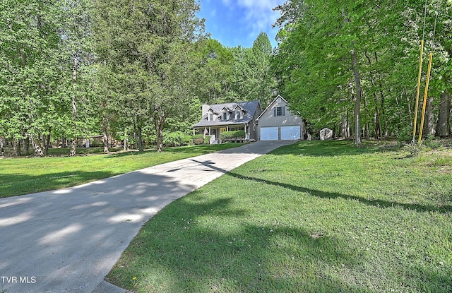 traditional-style home with a wooded view, a garage, a front yard, and concrete driveway