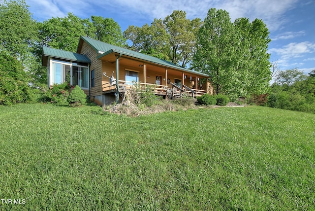 rear view of property with a porch, a yard, and metal roof