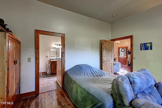 bedroom with baseboards, dark wood-style floors, and connected bathroom