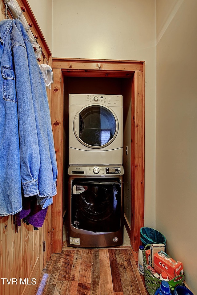 clothes washing area featuring laundry area, stacked washer / drying machine, and wood finished floors