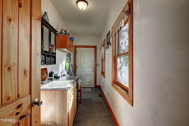 hall featuring a sink, baseboards, dark colored carpet, and visible vents