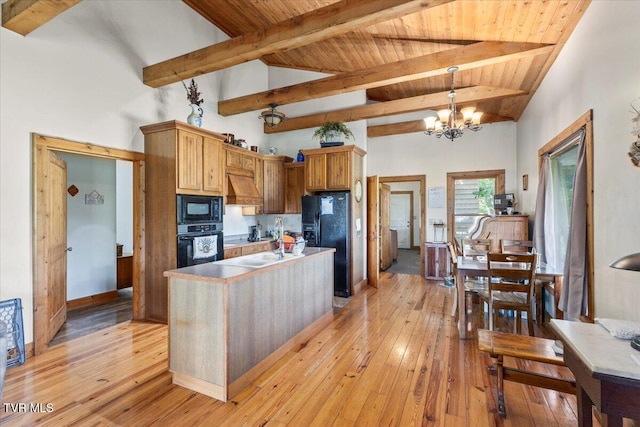 kitchen featuring custom exhaust hood, black appliances, light wood-type flooring, and beam ceiling