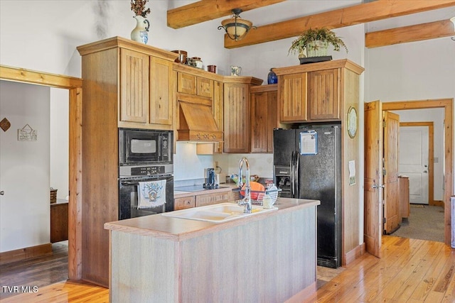 kitchen featuring light countertops, premium range hood, beamed ceiling, black appliances, and light wood-style floors