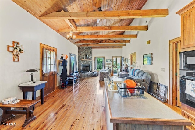 living room with light wood-style floors, wood ceiling, a fireplace, and beam ceiling