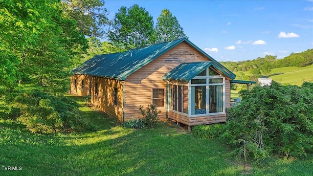 view of property exterior with a yard, metal roof, and a sunroom