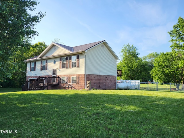 rear view of property with brick siding, fence, and a yard