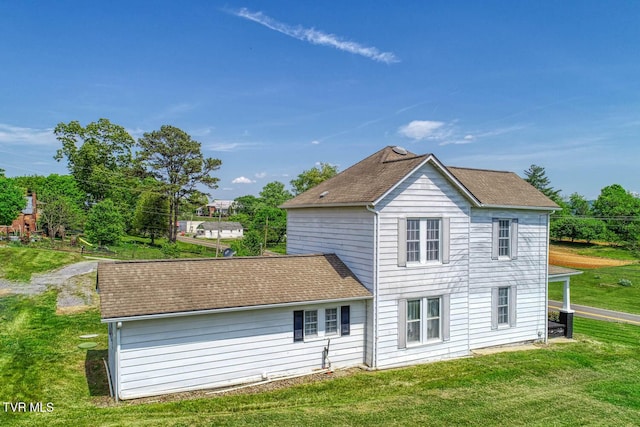 back of property with a lawn and roof with shingles