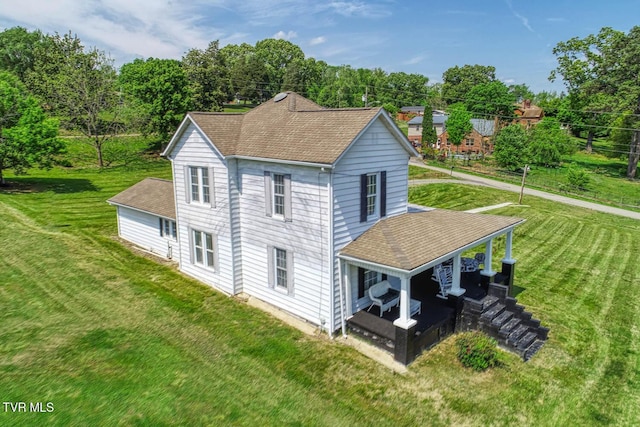 exterior space with roof with shingles and a yard