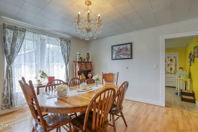 dining room featuring crown molding, light wood-style flooring, baseboards, and a notable chandelier