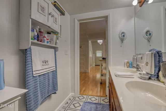 full bath featuring baseboards, a sink, and double vanity