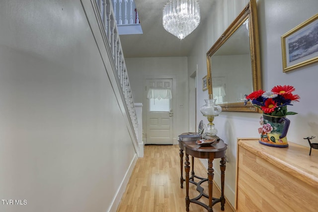doorway to outside with baseboards, stairs, light wood-style flooring, and a chandelier