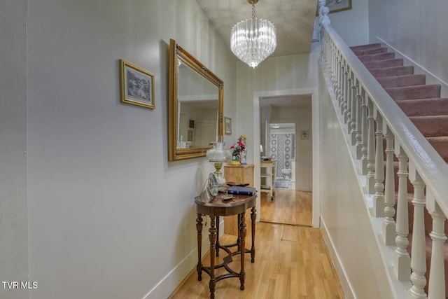 foyer entrance featuring baseboards, stairs, wood finished floors, and a chandelier
