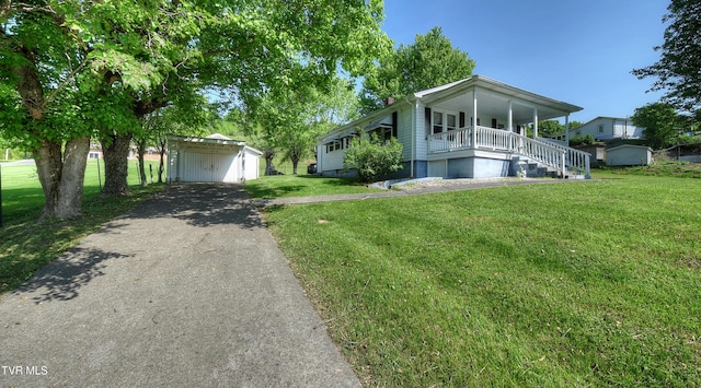 ranch-style house featuring a porch, an outbuilding, a front yard, and a carport