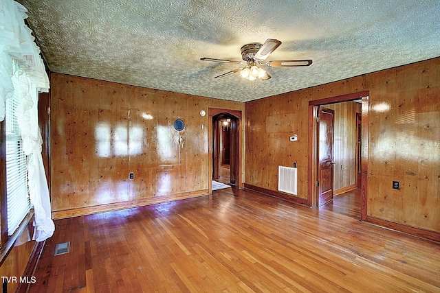 spare room with visible vents, arched walkways, baseboards, and ceiling fan
