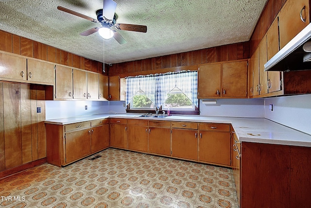 kitchen featuring a sink, light countertops, a textured ceiling, a ceiling fan, and under cabinet range hood