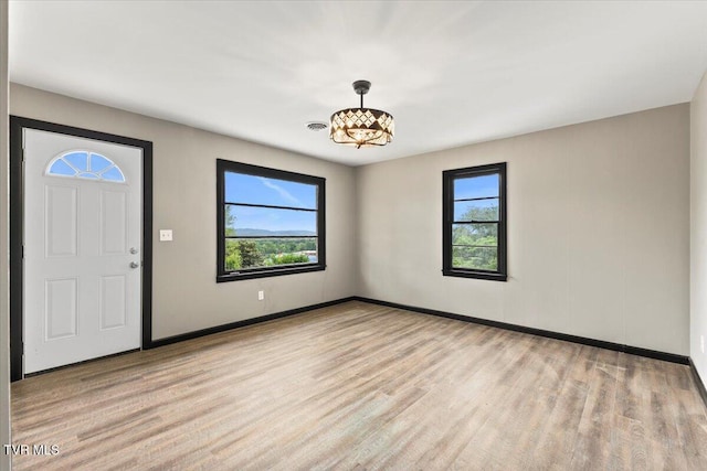 foyer entrance featuring a healthy amount of sunlight, baseboards, wood finished floors, and a chandelier