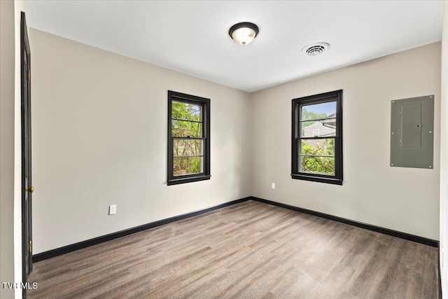 unfurnished room featuring visible vents, plenty of natural light, wood finished floors, and electric panel
