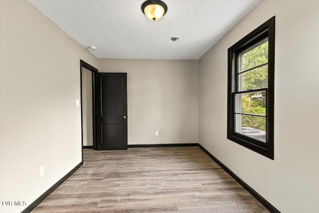 spare room featuring light wood-style floors and baseboards