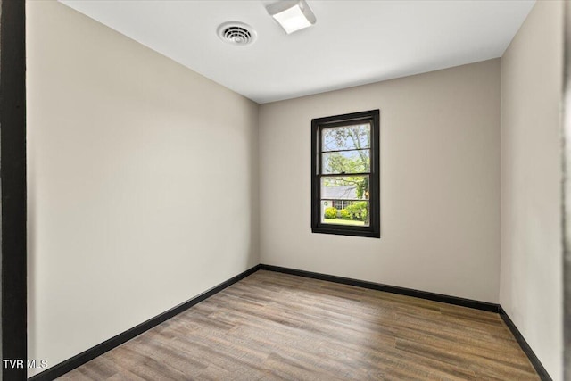 empty room with visible vents, light wood finished floors, and baseboards