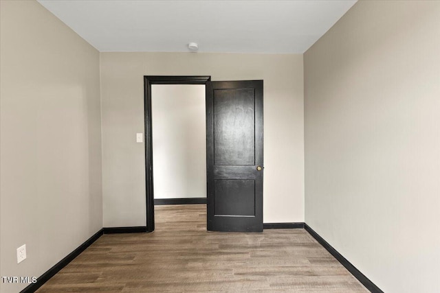 empty room with baseboards and wood finished floors