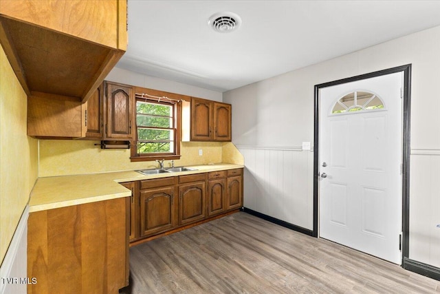 kitchen with brown cabinetry, visible vents, light countertops, a sink, and light wood-style flooring