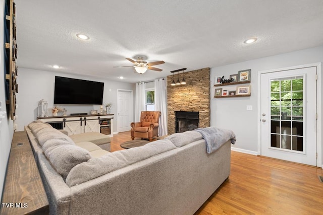 1008 Cox Trail Pl, Kingsport, TN 37660 - living room with a stone fireplace, a ceiling fan, plenty of natural light, a textured ceiling, and light wood-style floors