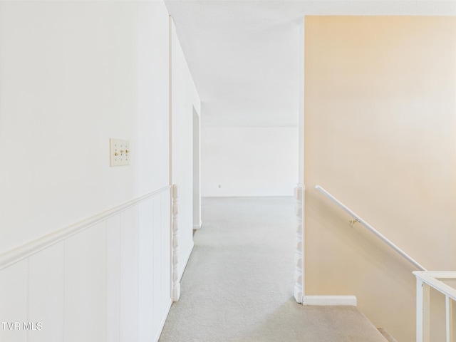hall featuring light colored carpet and an upstairs landing