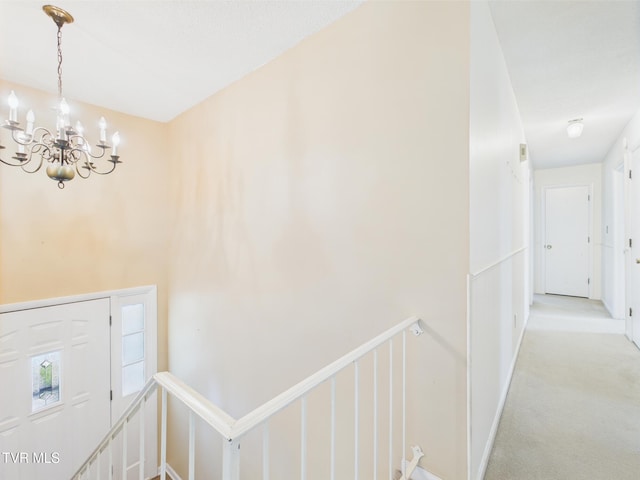 interior space with carpet flooring, a chandelier, and an upstairs landing