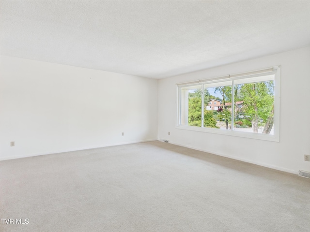 unfurnished room featuring baseboards, light colored carpet, and visible vents