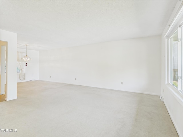interior space with baseboards, a notable chandelier, and light carpet