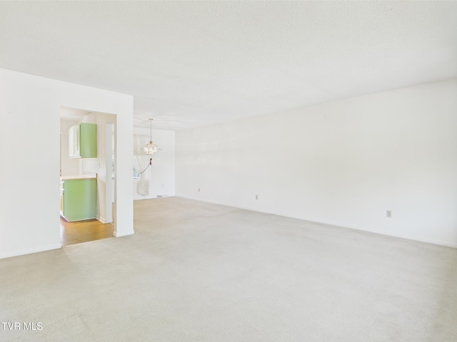empty room featuring an inviting chandelier and light carpet