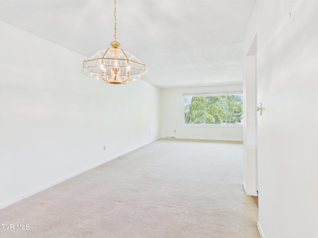 carpeted spare room with baseboards and a notable chandelier