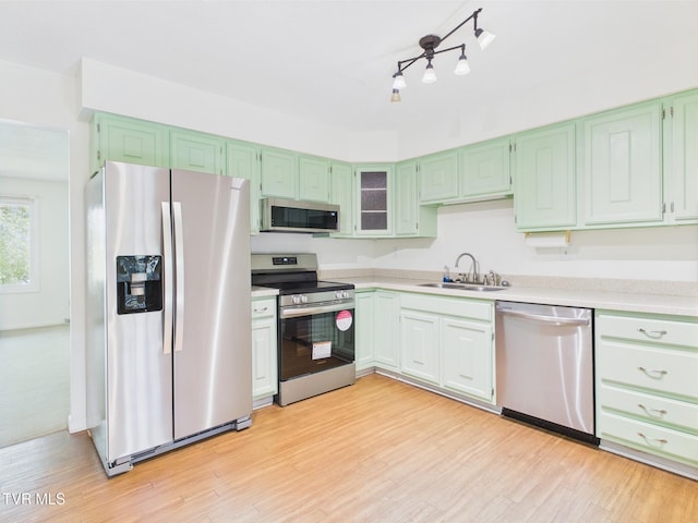 kitchen featuring light countertops, appliances with stainless steel finishes, a sink, and light wood-style floors