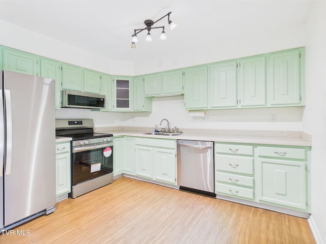 kitchen with a sink, appliances with stainless steel finishes, light wood finished floors, and light countertops