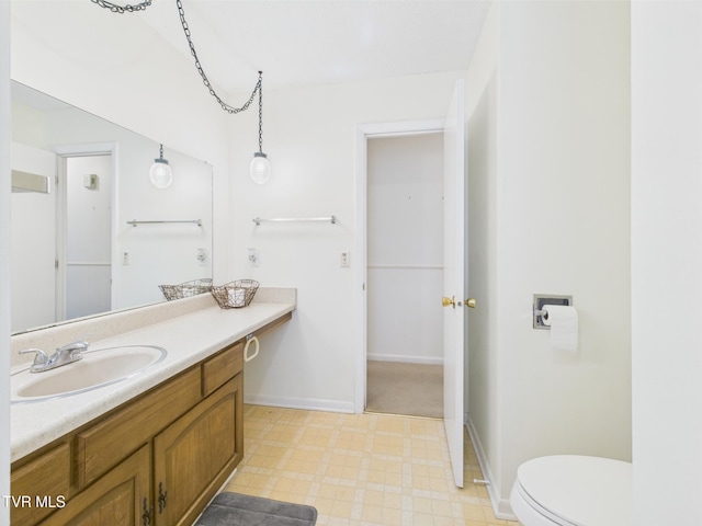 bathroom with toilet, tile patterned floors, baseboards, and vanity