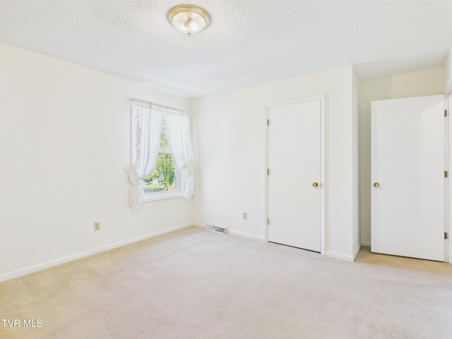 unfurnished bedroom featuring visible vents, carpet flooring, a textured ceiling, and baseboards