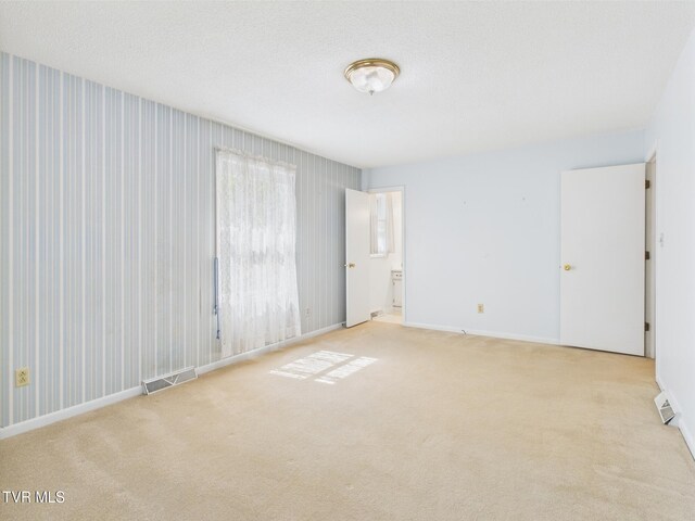 spare room with light colored carpet, baseboards, and visible vents