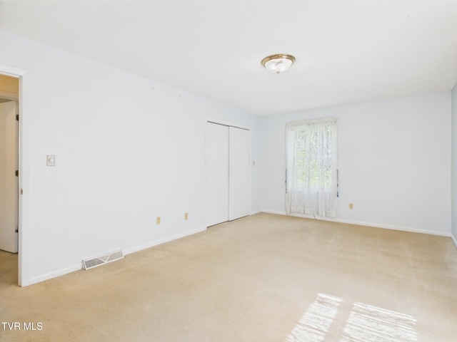 unfurnished room with baseboards, visible vents, and light carpet