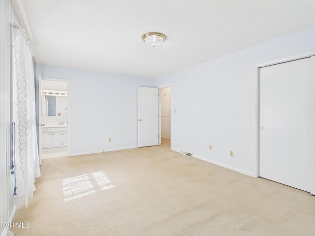 unfurnished bedroom featuring baseboards, carpet, connected bathroom, and visible vents