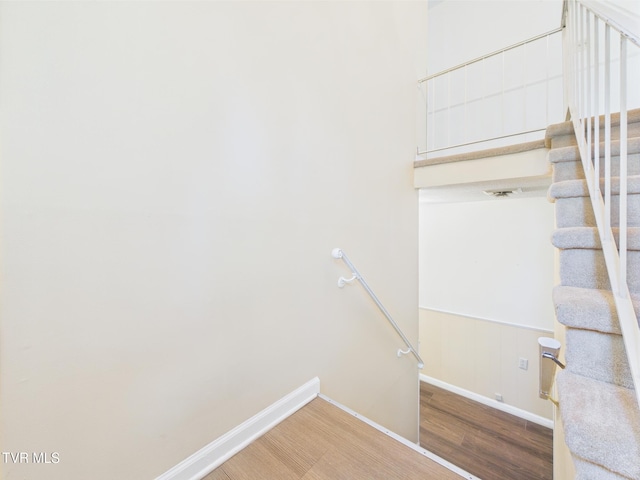 staircase featuring baseboards and wood finished floors